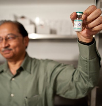 Man holding a vaccine vial labeled with a vaccine vial monitor sticker.