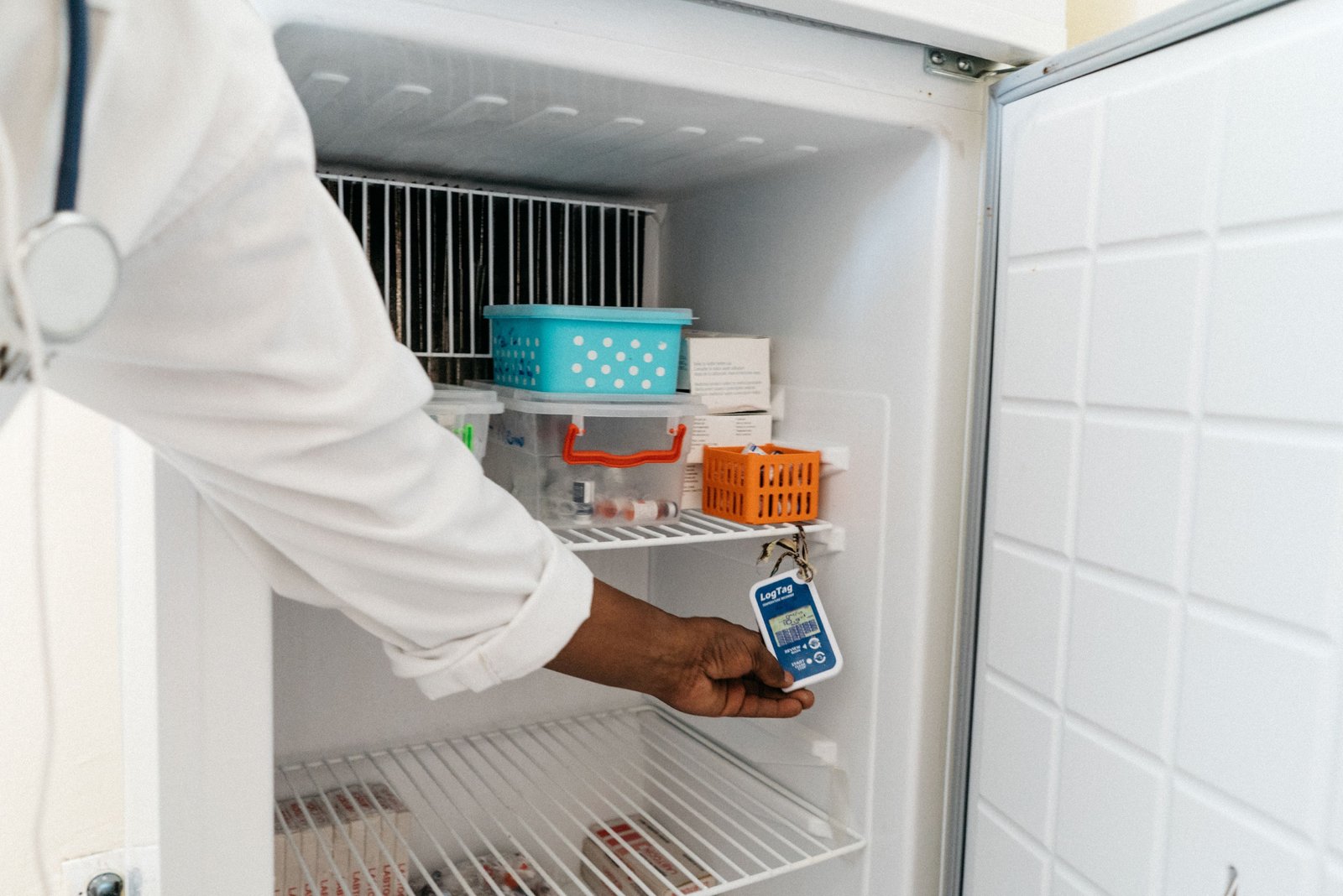 Photo: A health worker at the Thiénaba health post in Senegal shows a sensor in a refrigerator that monitors the temperature. Credit: PATH/Gabe Bienczycki