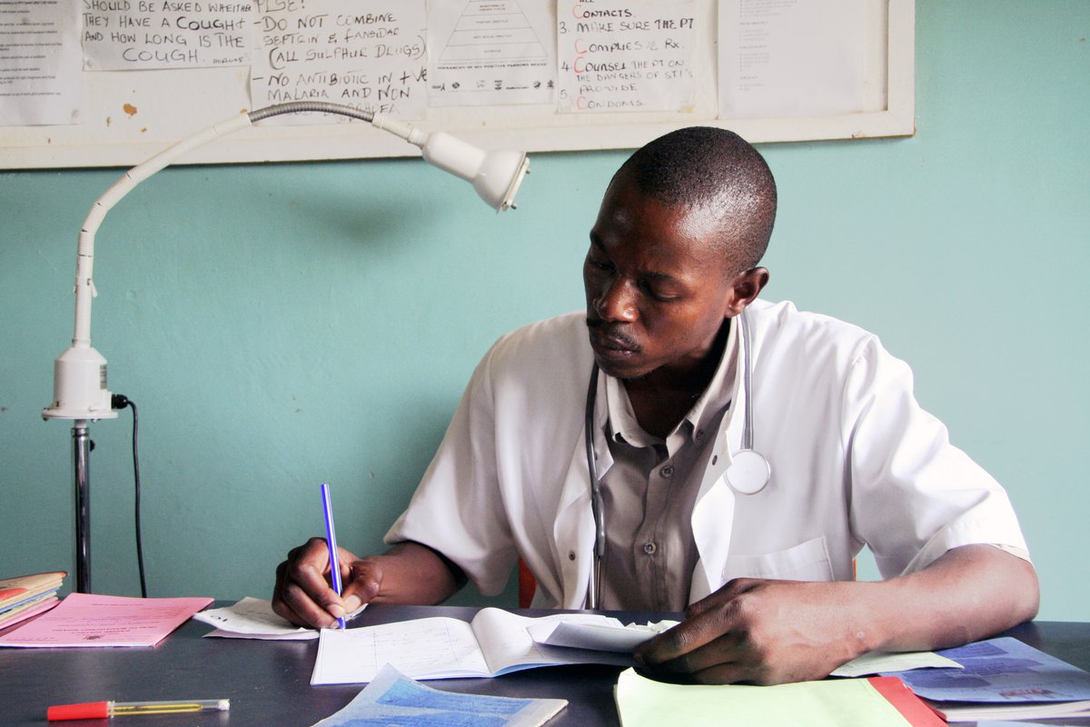 Health worker writing at desk in clinic. PATH/David Jacobs